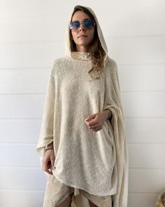 "Off White Knit Cotton Hooded Cape. Cowl Neck Hoodie. Poncho Style. This gorgeous soft tunic is lovingly handmade from an up-cycled cotton blend. It is a part of the collection \"Ceremony White\" - a collection of dresses and pants created specifically for your ceremony journeys, kundalini yoga, sound baths and mediation. Inspired by silent mediation and love for comfortable wear. Material: Up-cycled knit cotton. Very soft, light weight and flowing. Size: One size Overall Length: about 42 in. Ov Oversized Knitted Hoodie Sweater, White Knitted Hooded Sweater, White Hooded Knitted Sweater, Beige Hooded Poncho For Fall, Cozy Hooded Soft Knit Sweater, Cozy Solid Poncho For Winter, Cozy Poncho For Winter, Oversized Soft Knit Hoodie, Cozy Long Sleeve Poncho One Size