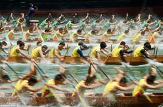 a large group of people in canoes with paddles