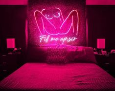 a pink neon sign on the wall above a bed