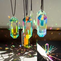 three different colored crystal pendants hanging from black cord with light shining through them and on the ground