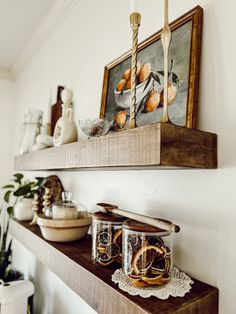 a shelf with two mugs on top of it and some pictures above the shelves