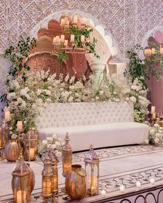 a white couch sitting on top of a table next to candles and flowers in vases