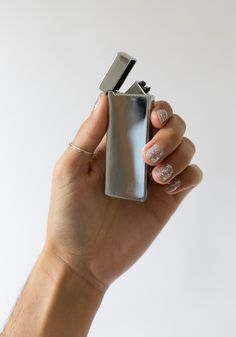 a person holding a lighter in their right hand and wearing nail polish on the other