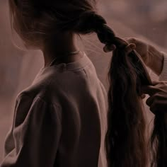 a woman is braiding her long hair