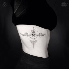 a woman's stomach with an arrow and compass tattoo on her side ribcage