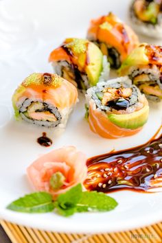 several sushi rolls on a white plate with sauce