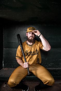 a man with a beard sitting on a bench holding a baseball bat in his hand