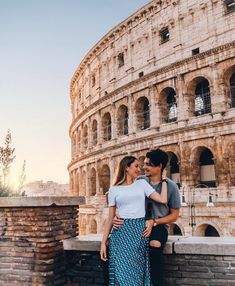 a man and woman standing in front of the colossion with their arms around each other