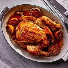 a pan filled with chicken and vegetables on top of a table next to utensils