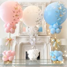 some balloons are in front of a fire place with butterflies on them and one balloon is pink, the other blue