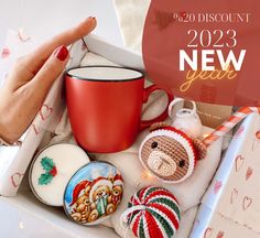 a woman's hand is holding a red cup and some christmas decorations in a box