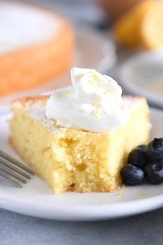 a piece of cake with whipped cream and blueberries on a plate next to a fork