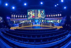 an empty sports arena with several large screens on the wall and blue lights in the ceiling