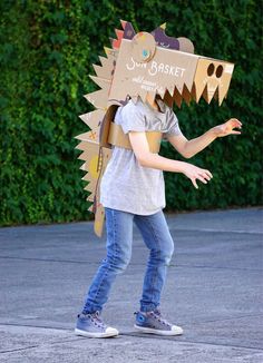 a young boy wearing a cardboard box shaped like a dragon