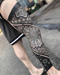 a man's leg with an intricate black and white tattoo design on his arm