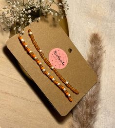 two orange and white beaded bracelets sitting on top of a brown card board