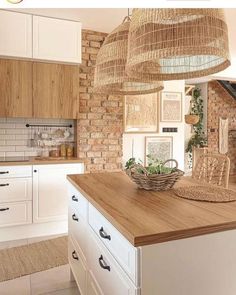 a kitchen with white cabinets and wooden counter tops, hanging baskets over the island in front of the sink