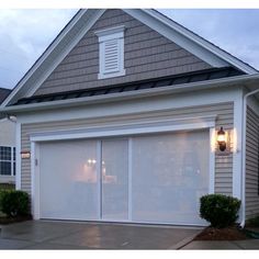 a white garage door is open in front of a house