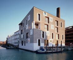 an apartment building sitting on the side of a body of water next to a dock