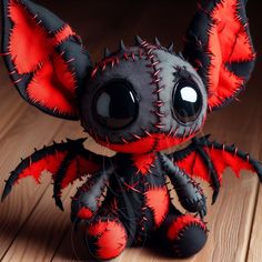 a black and red stuffed animal sitting on top of a wooden floor