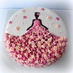 a cake with pink and white frosting on it that has a woman's dress made out of flowers