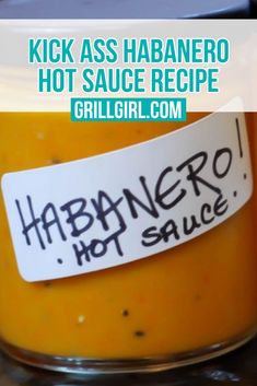 a jar filled with hot sauce sitting on top of a counter next to a sign