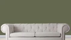 a white couch sitting on top of a hard wood floor next to a green wall