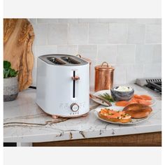 a toaster sitting on top of a kitchen counter next to plates of food and utensils