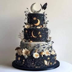 a three tiered cake decorated with flowers, butterflies and the moon is on display