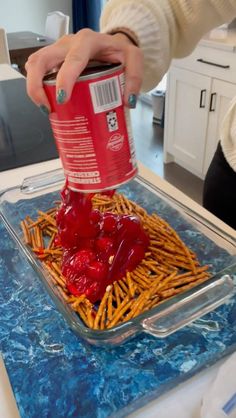 someone is pouring ketchup onto some food in a container on top of a table