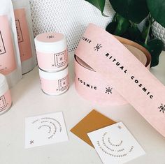 some pink packaging on a white table next to plants and paper with the words natural cosmetic written on it