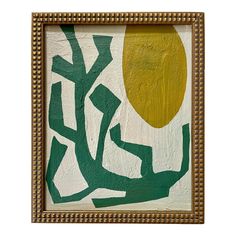 an abstract painting with green and yellow colors in a gold frame on a white wall