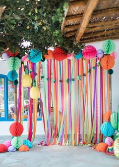 colorful paper balls and streamers decorate the entrance to a home in an area that is decorated with palm trees