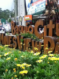 a sign that says baquo city winery plaza in front of some yellow flowers