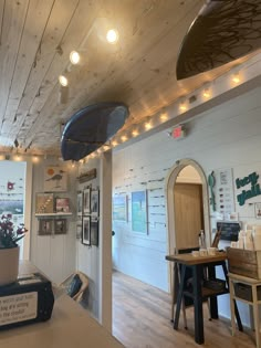 the inside of a store with lights and pictures on the wall, including a potted plant