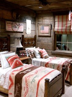 two twin beds in a rustic bedroom with american flags on the wall and wood paneled walls