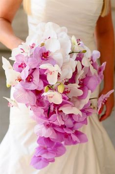 a bride holding a bouquet of pink and white orchids in her wedding day dress