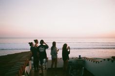 several people standing on a pier looking out at the ocean and one person riding a bike