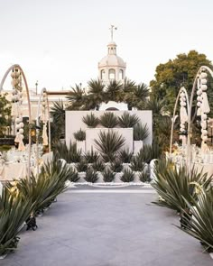 an outdoor wedding venue with white and gold decorations, palm trees and tall buildings in the background