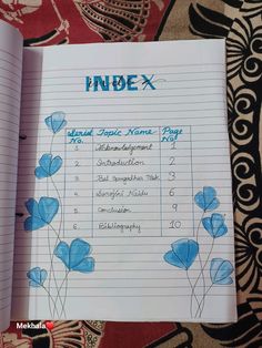 an open notebook with blue flowers on it and the words index written in black ink