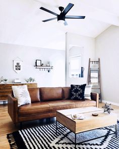 a brown leather couch sitting on top of a black and white rug