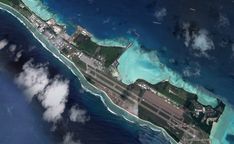 an aerial view of the island in the middle of the ocean with clouds around it