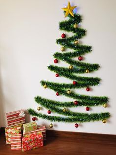 a christmas tree with presents under it on the floor next to a wall mounted ornament