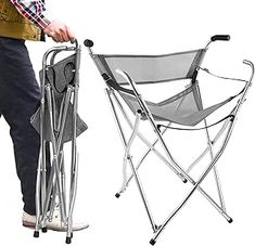 a man standing next to a folding chair with the seat up and holding it in his hand