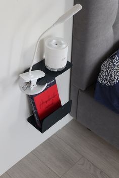 a book shelf with a lamp on top of it next to a gray couch and blue throw pillow