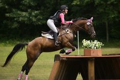 a woman riding on the back of a brown horse next to a wooden table with flowers