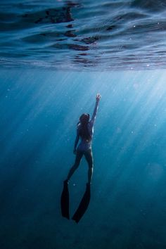 a woman swimming in the ocean with her arms up