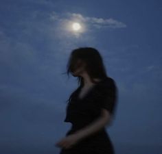 a woman standing in front of the moon with her hand on her hip and looking down