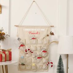 a christmas calendar hanging on a wall next to a table with presents and a lamp