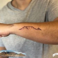 a man with a mountain tattoo on his arm